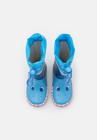 Blauwe rubberen regenlaarzen met haai-ontwerp; heeft ronde neuzen, een trekkoordsluiting en een rood tandpatroon langs de buitenzool.