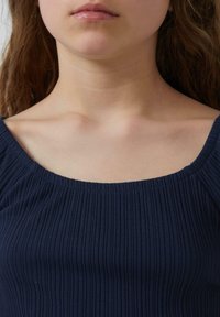 Marineblauwe ribbeltop met een ronde halslijn en een een gestructureerde stof, die een aansluitend ontwerp toont en subtiele elastische accenten op de schouders.