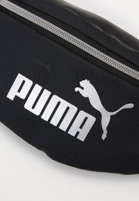 Zwarte stoffen tas met een zilveren rits, prominente witte "PUMA" logo en een springende poema silhouet. Textuur oppervlak.