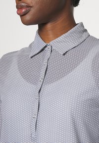 Skjorta med krage som har ett texturerat mönster av tunna, horisontella linjer i svart och vitt, med knäppning framtill och slät tyg.