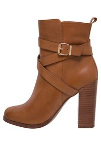 Hnědá kožená kotníková bota s viditelným páskem na sponu, kulatou špičkou a blokovým podpatkem se zdobením vodorovnými drá�žkami.