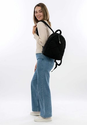 Black quilted backpack with a rounded shape, featuring a top handle and adjustable straps. Smooth texture with metallic zipper hardware.