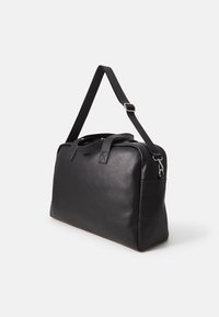 Bolso de cuero negro con dos asas superiores, correa de hombro ajustable, cierre de cremallera y un bolsillo lateral para almacenamiento adicional. Forma rectangular.