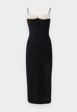 Robe noire près du corps avec des bretelles spaghetti, mettant en avant une rangée de fausse fourrure blanche au niveau du col et une fente sur le côté. Tissu lisse et extensible.