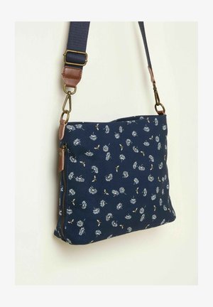 Tumesinise värvi lõuendist õlakott lillemustriga ja kollaste aktsentidega. Omaduseks on lukuga tasku ja reguleeritav kangast rihm, millel on pruunist nahast detailid.