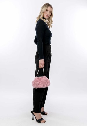 Borsa fluffy rosa con manico a catena argento, abbinata a un top aderente nero a maniche lunghe e pantaloni neri a vita alta.