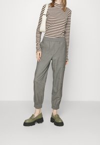 Striped brown and beige long-sleeve top paired with light gray tapered trousers featuring elastic cuffs, set against a white background.