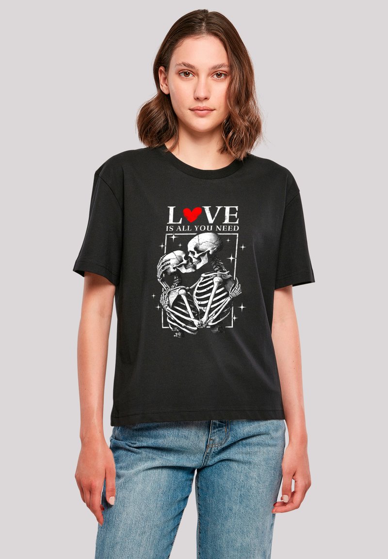 Black cotton t-shirt featuring a skeletal graphic with red heart accents and the text "LOVE IS ALL YOU NEED." Short sleeves, relaxed fit.