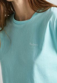 Jasnoniebieska koszulka z miękkiej bawełny. Posiada okrągły dekolt oraz małe białe logo "Pepe Jeans London" na piersi.