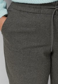 Dunkelgraue, taillierte Sweatpants aus weichem Stoff, mit einem Kordelzugbund, seitlichen Taschen und einer glatten Textur.