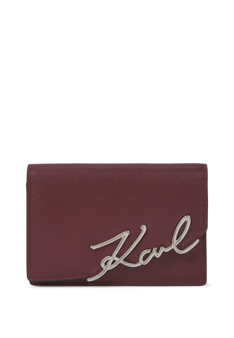 Bordeaux leren portemonnee met een gladde textuur, voorzien van een opvallend zilveren "Karl" logo als sluiting. Compact rechthoekig ontwerp.