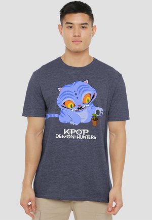 Navyblaue Baumwoll-T-Shirt mit einem Cartoon-Katzenmotiv, das große gelbe Augen und eine Pflanze in einem Topf zeigt. Der Text lautet: "KPOP DEMON HUNTERS."