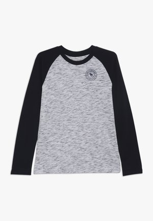 Langärmeliges Raglanshirt mit schwarzen Ärmeln und grauem, strukturiertem Körper, versehen mit einem kleinen kreisförmigen Logo auf der linken Brust.