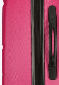 Valigia rigida rosa con superficie texturizzata, zipper e maniglia neri, e una forma aerodinamica per durabilità e facilità d'uso.