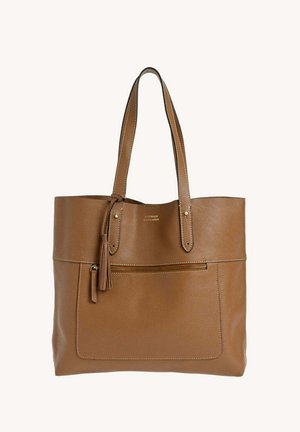 Sac fourre-tout en cuir marron avec double anses, poche zippée à l'avant et détail pompon sur fond uni.