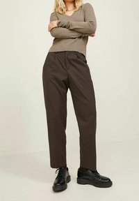 Bruna skräddarsydda byxor med rak passform, tillverkade av mjukt tyg. Kombinerat med en beige ribbad stickad topp och svarta snörskor.