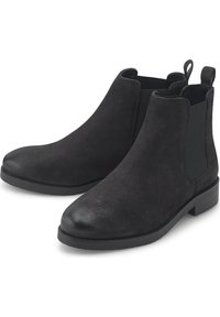 Botas Chelsea de ante negro con paneles elásticos en los laterales, puntera redonda, tacón bloque bajo y tira para tirar en la parte trasera. Suela plana de goma.