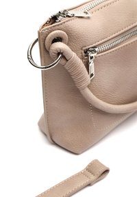Sac à main en cuir beige avec une forme structurée, doté de deux compartiments zippés et d'une poignée enroulée. Des accents en métal argenté sont présents.