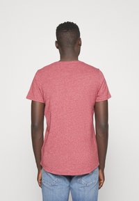 Červené melírované tričko s krátkým rukávem, kulatým výstřihem, vyrobené z měkkého materiálu, s mírně zakulaceným spodním lemem a volným střihem.