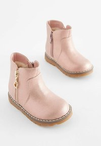 Rosa Glitzer-Ankle Boots mit seitlichen Reißverschlüssen, weicher Innenauskleidung, Gummisohle und dekorativem Herzanhänger am Reißverschluss.
