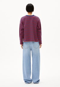 Rot- und marineblau gestreiftes Langarmshirt mit Rundhalsausschnitt, kombiniert mit hellblauen, weit geschnittenen Jeans mit Gesäßtaschen.