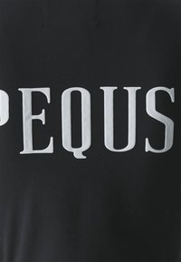 Svart tyg med stora, djärva, vita bokstäver som stavar "PEQUIS." Texturen verkar jämn, med en lätt lyster från tygets yta.