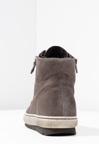 Brown suede ankle boot with side zipper, textured beige rubber sole, and black treaded outsole, shown from back angle on white background.