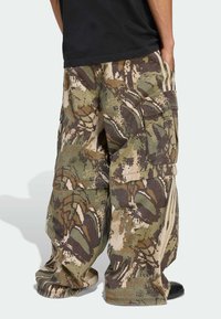 Pantalones cargo en patrón de camuflaje, con grandes bolsillos laterales, un corte suelto y acentos en beige contrastantes a lo largo de las costuras laterales.