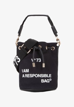 Zwarte canvas emmer tas met gouden hardware, verstelbare schouderriem, trekkoordsluiting en bedrukte tekst: "IK BEN EEN VERANTWOORDelijke TAS."