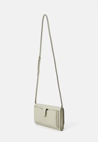 Borsa a tracolla in ecopelle verde chiaro, con forma rettangolare, tracolla regolabile, patta pieghevole e tasca frontale.