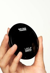 Compatto rotondo nero con una finitura liscia, etichettato "MAT FACE POWDER" e "LAYLA COSMETICS MADE IN ITALY" in testo bianco.