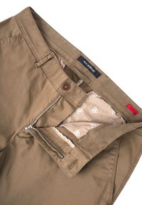Khaki broek met een rits en knoopsluiting. Het interieur heeft een lichtgepatroneerde voering. De stof is soepel met subtiele stikselaccenten.