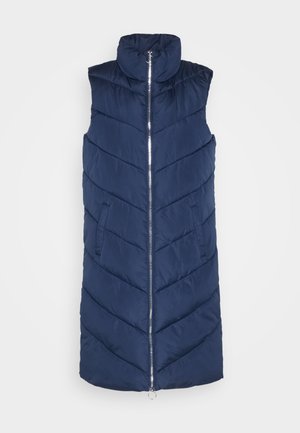 Tengerész kék puffervest magas gallérral, elülső cipzárral és két oldalsó zsebbel. Chevron mintázatú és sima textúrájú.