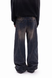 Baggy denim jeans in a faded blue hue, featuring large pockets and a distinct vertical seam design. Textured fabric with a relaxed fit.