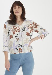 Blusa floreale color crema, con motivi marroni, lavanda e blu scuro. Tessuto morbido con scollatura a V e maniche a 3/4, vestibilità morbida.