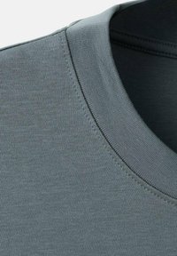 Harmaa lyhythihainen t-paita, jossa on teksturoitu, sileä kangas. Kauluksella on tiiviisti ommellut saumat kaulan ja hartioiden alueella.