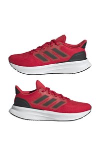 Zapatillas deportivas rojas con una parte superior de tejido texturizado, tres rayas grises en los laterales, detalles en negro, una suela acolchada y una entresuela blanca.