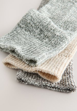 Trzy rolki dzianiny w kolorach szarym, beżowym i kremowym. Każda ma teksturowany, prążkowany wzór z miękkimi krawędziami i luźnym splotem.