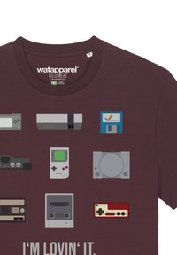 Bordeauxrotes T-Shirt mit grafischen Designs verschiedener Retro-Spielkonsolen und -geräte in gedämpften Farben, mit dem Text "I'M LOVIN' IT" am unteren Ende.