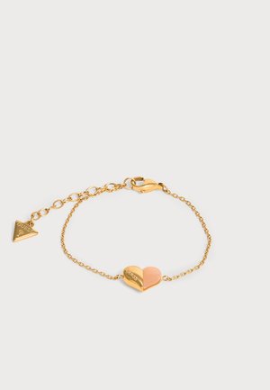 Bracelet délicat en chaîne dorée avec un pendentif cœur bicolore et un fermoir réglable doté d'une petite étiquette triangulaire Guess.