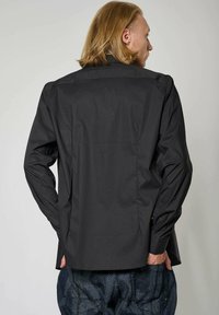 Zwart overhemd met knopen, met een op maat gemaakt ontwerp, lange mouwen, een rugpas, en een gladde stoftextuur. Gstyled met een patroon van blauwe broeken.