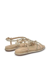 Nudesandalen met glinsterende banden, versierd met kleine edelstenen. Platte zool, zachte suède afwerking, verstelbare enkelriem voor een veilige pasvorm.