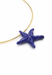 Pendentif en forme d'étoile de mer en céramique bleue sur une fine chaîne en métal doré. L'étoile de mer présente des détails texturés et une finition brillante.