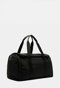 Sac de sport noir en matériau synthétique, doté de deux poignées supérieures, d'une fermeture éclair et d'une poche latérale avec un détail de sangle tissée.