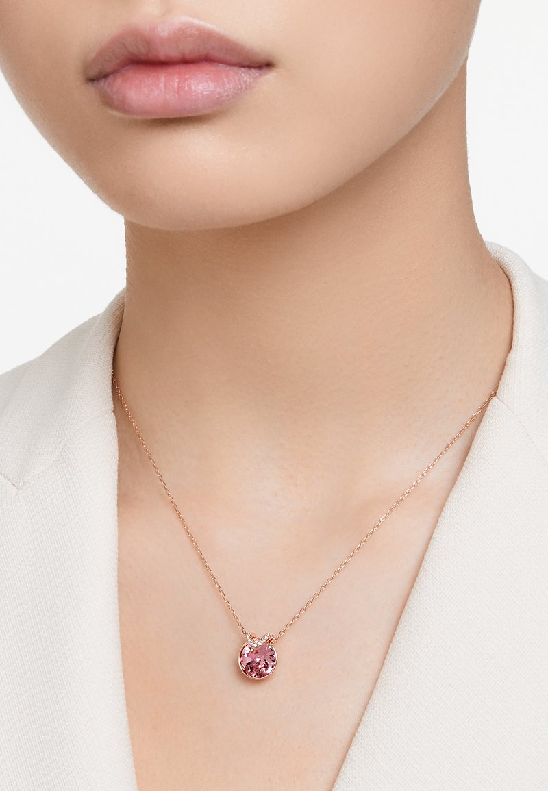 Náhrdelník z růžového zlata s kulatým růžovým drahokamem jako přívěskem. Náhrdelník má jemný řetízek a jednoduchý design zapínání.