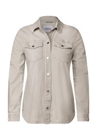 Camicia beige chiaro con sottili righe verticali. Presenta una chiusura con bottoni frontale, due tasche sul petto con pattine e un colletto classico. Materiale in cotone.