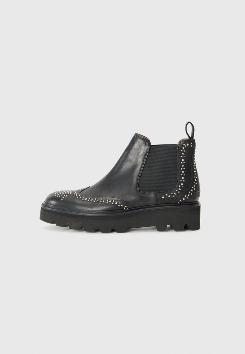 Botas Chelsea de cuero negro con acentos de remaches, paneles laterales elásticos, una lengüeta y una suela gruesa con tacos.