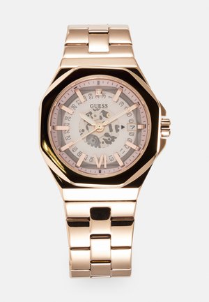 Rose gold watch with octagonal face, white patterned dial, and analog display. Metal link bracelet features polished finish and clasp closure.