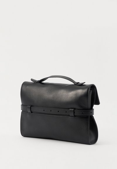 Sac en cuir noir avec une texture lisse, fermeture à rabat et une sangle ressemblant à une ceinture. Présente un design structuré et une poignée supérieure pour le transport.