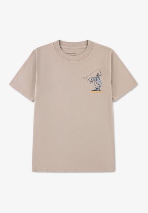 T-shirt beige à manches courtes avec un petit graphique représentant une personne pêchant en se tenant debout sur un requin, sur la partie gauche de la poitrine.